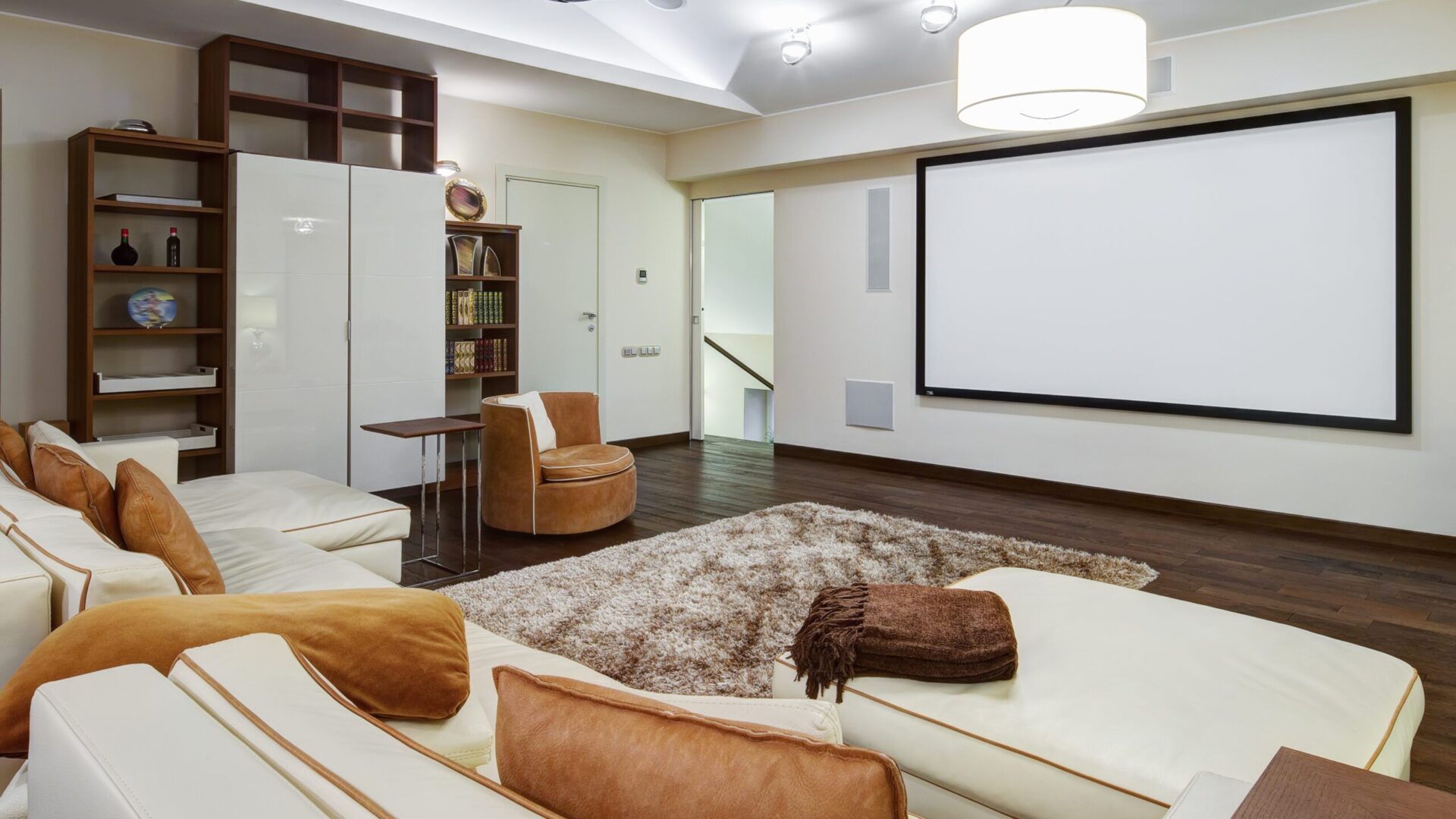 Home theatre with projector screen, cream lounges and timber shelving