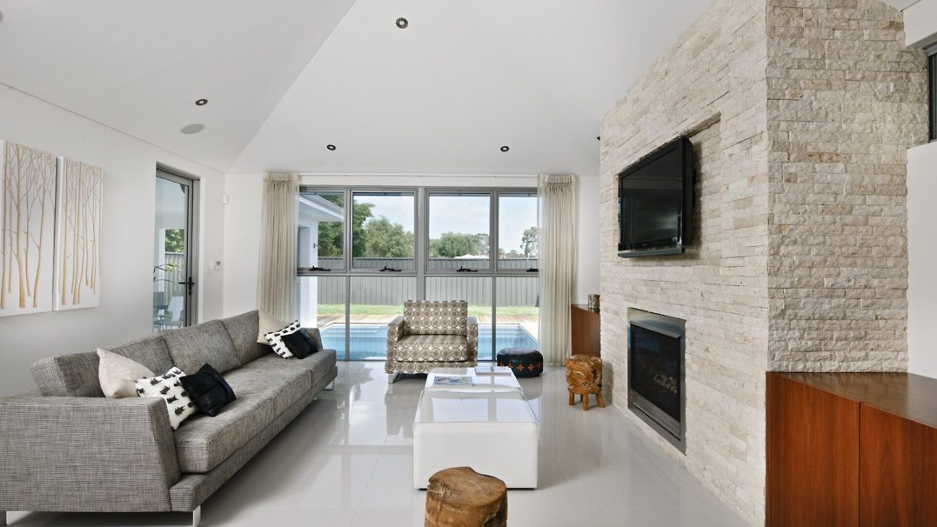 Living room with stone clad fireplace, raked ceiling and grey lounges