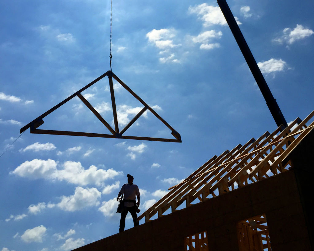 construction worker placing roof frame on home 