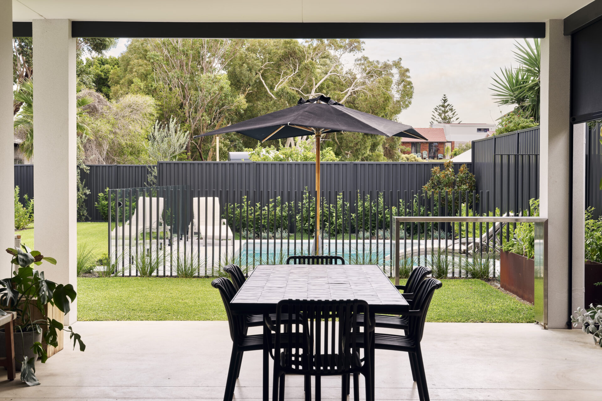 A outside patio with pool, umbrella and stone table in a lower chittering home in one of Perths safest suburbs