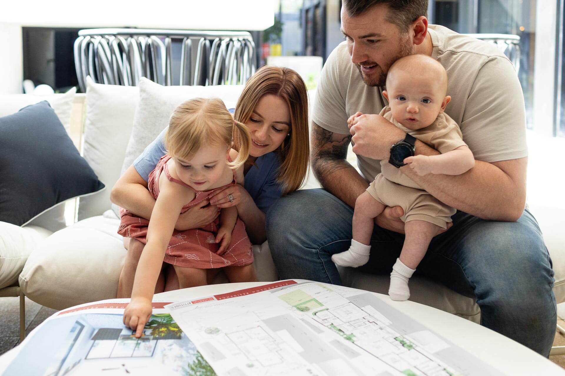 Toddler pointing at home plans while parents look on