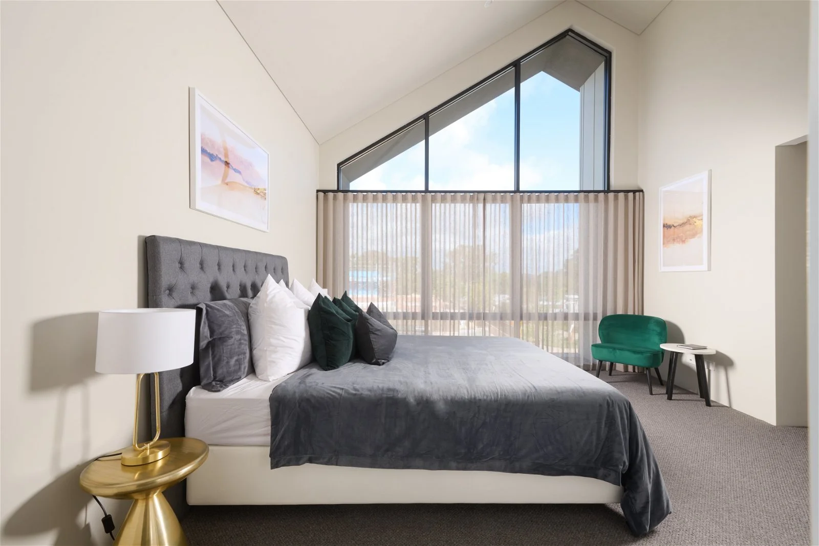 The upstairs master bedroom of a two-storey home containing a large window with a view and bedroom furniture including king sized bed.