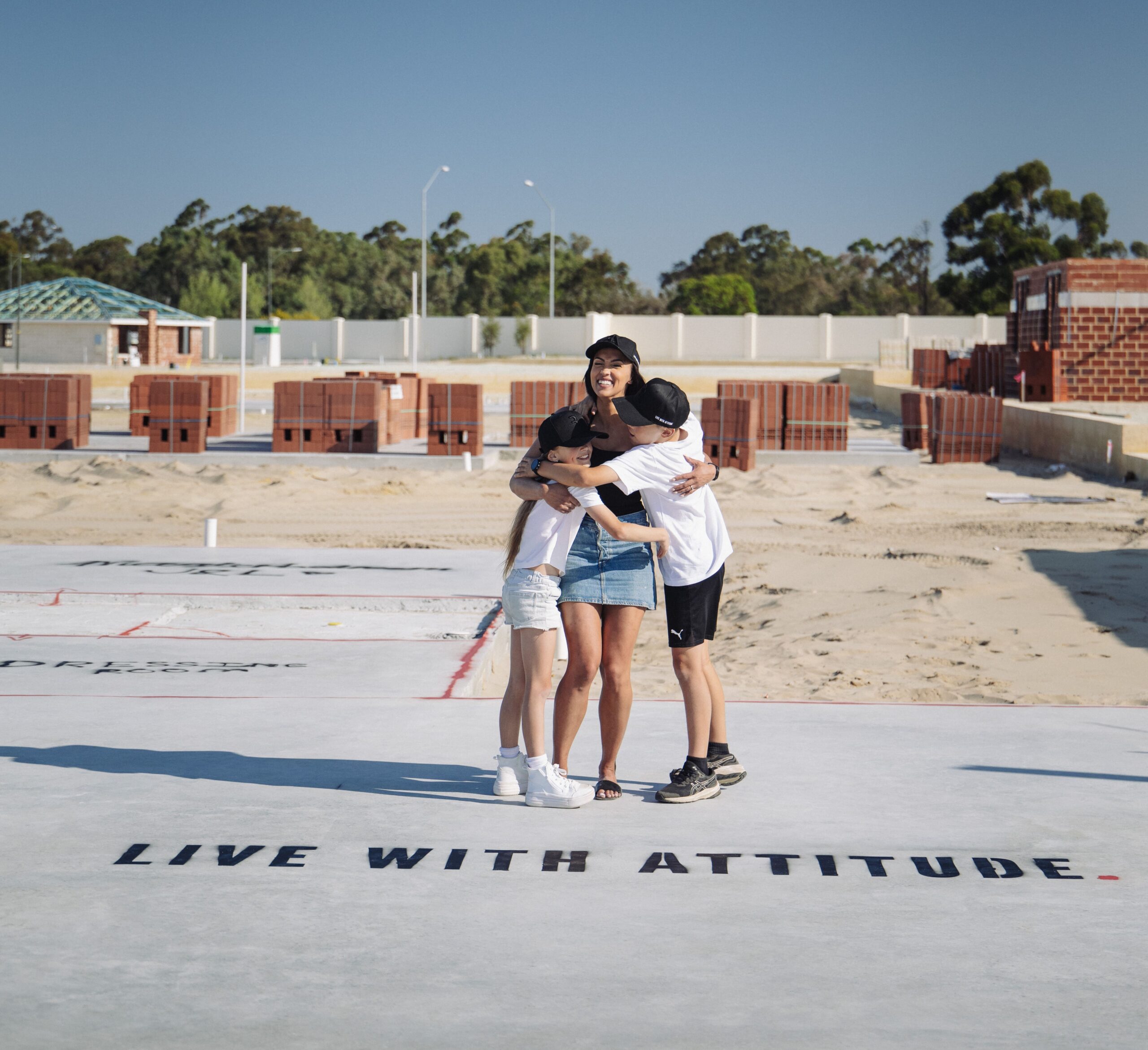 Family embracing on a new home slab painted with Live With Attitude