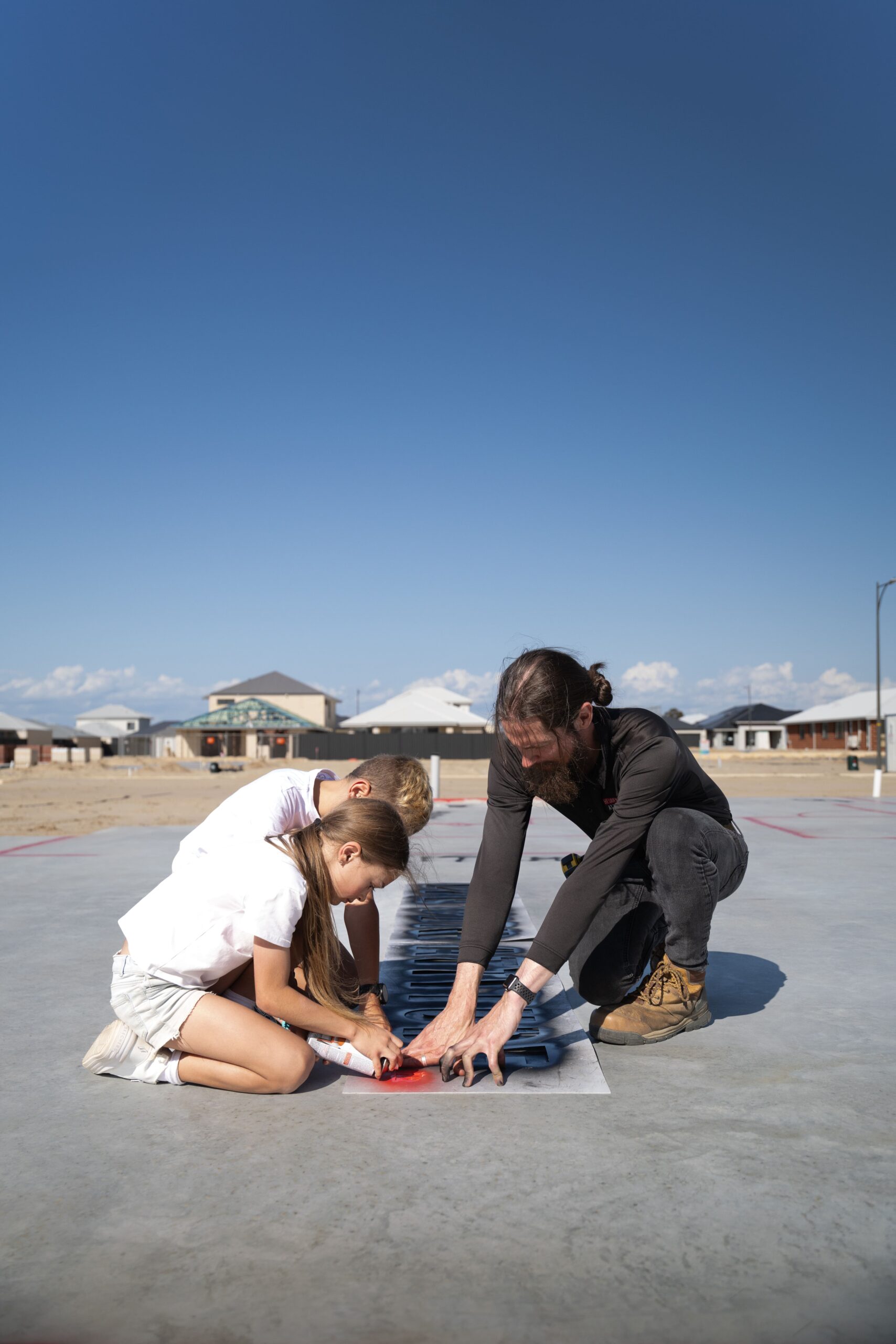 Children and a team member marking out a new home slab