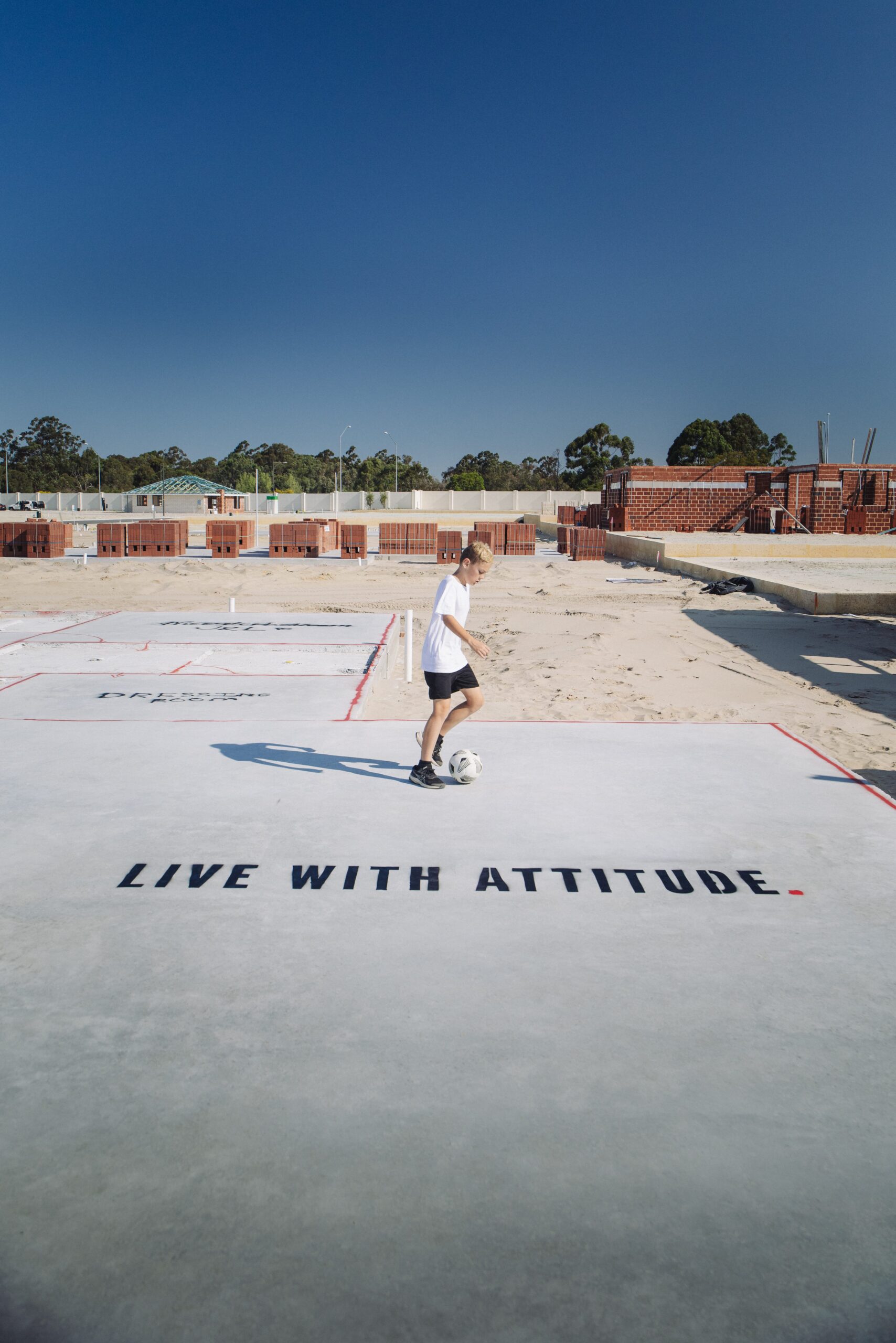 Child standing on a new home slab painted with Live With Attitude