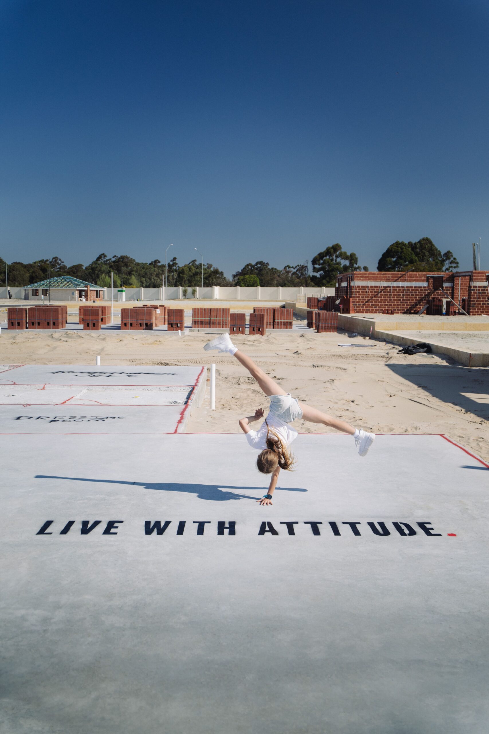 Child cartwheeling on a new home slab painted with Live With Attitude