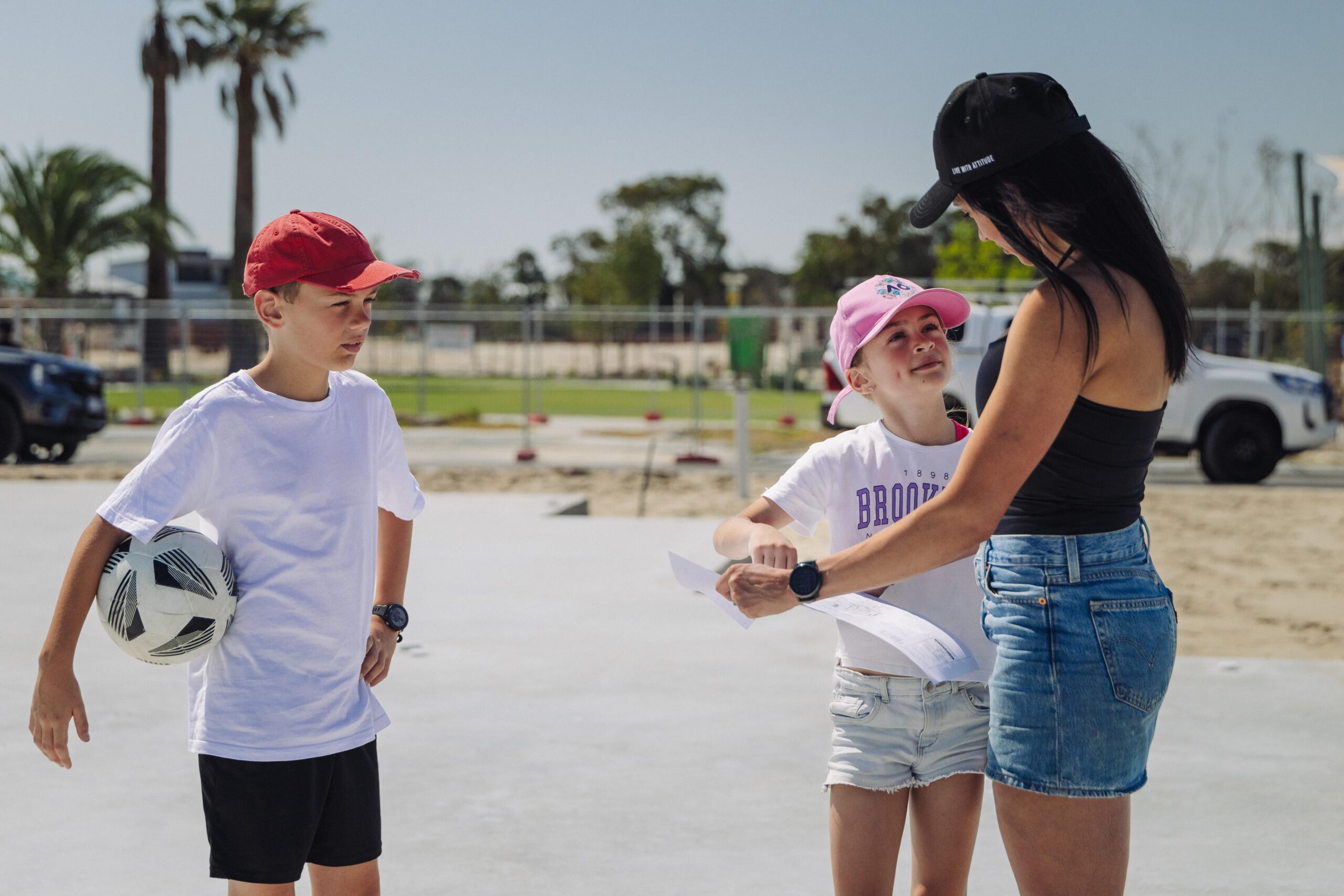 Children with a football while an adult reviews plans on site