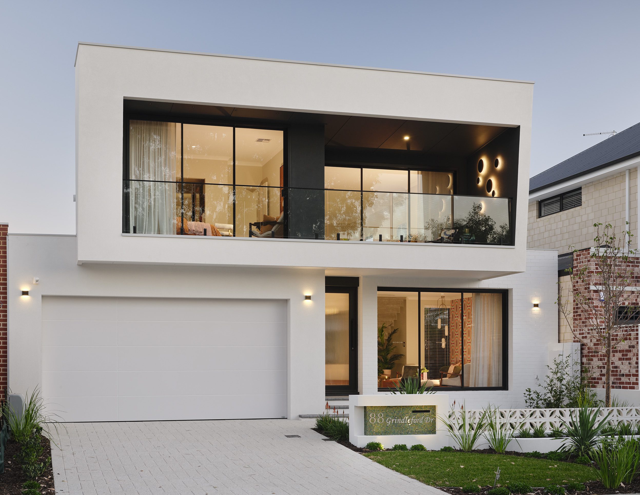 Two storey display home facade with white render, black framed windows and double garage