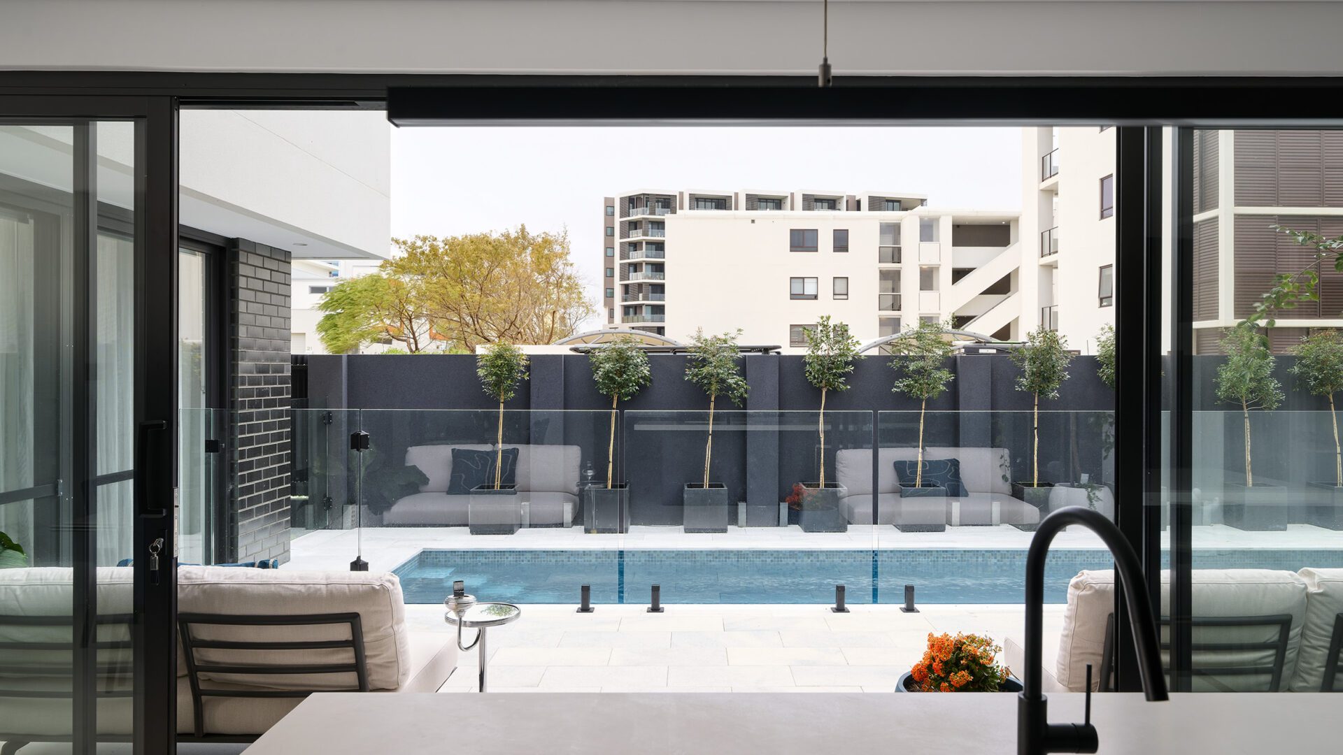 North Coogee client home indoor-outdoor connection view from kitchen island to the outdoor pool area.