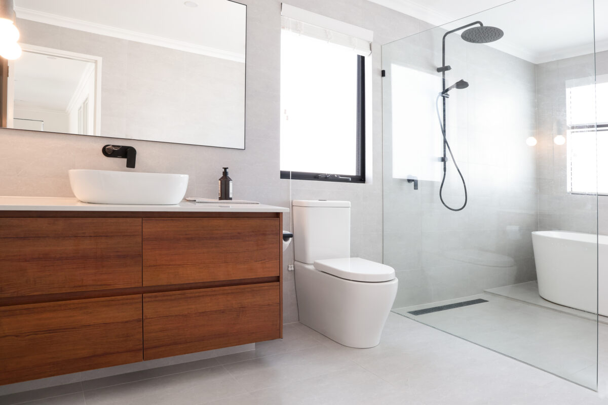 Large bathroom featuring a warm, dark wooden cabinetry and a standalone bathtub in the wet area. Built by Residential Attitudes.