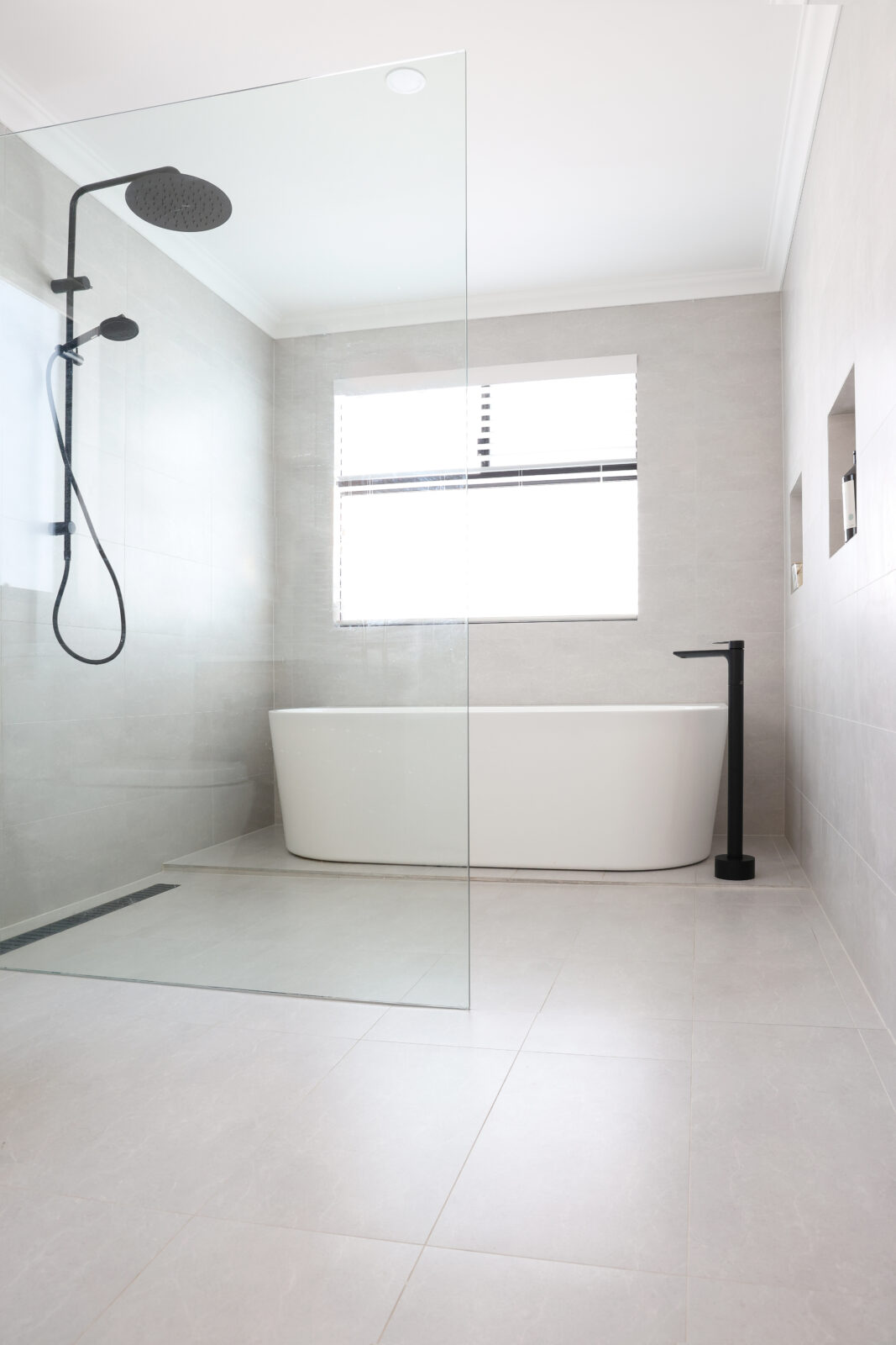 A large standalone bathtub with black tapware in the wet area of the bathroom. Built by Residential Attitudes.