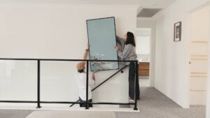 Residential Attitudes client Lana and her son, put up a framed painted artwork (painted by Lana) upstairs on the wall of this double storey home built by Residential Attitudes.
