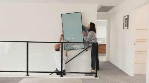 Residential Attitudes client Lana and her son, put up a framed painted artwork (painted by Lana) upstairs on the wall of this double storey home built by Residential Attitudes.