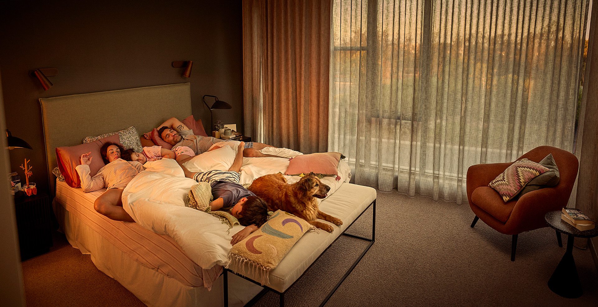 A family bundled together in the master/parents bedroom. At Residential Attitudes, this is what a perfect home for imperfect lives looks like. 